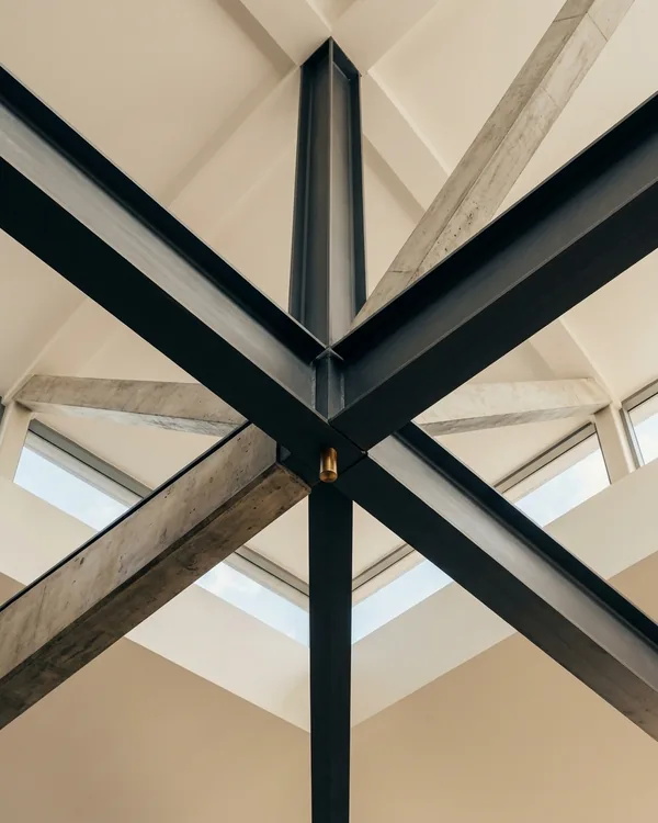 Steel beams meeting at a single point beneath a skylight