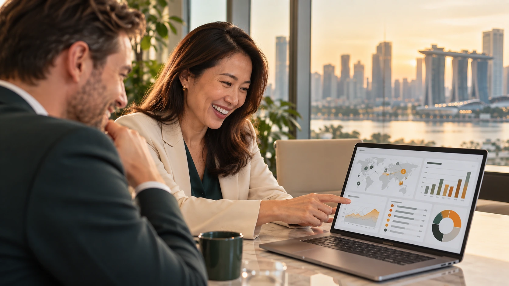 Two colleagues smiling over a laptop dashboard, Singapore skyline at sunset behind